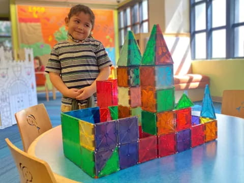 a boy standing next to a table with colorful blocks on it