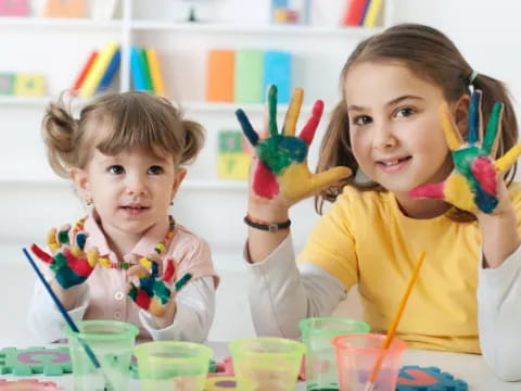 a couple of young girls with paintbrushes in their hands