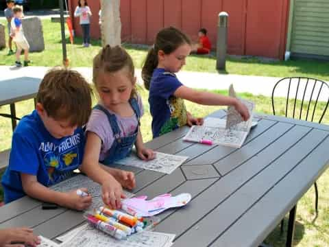 a group of children sitting at a table writing on paper