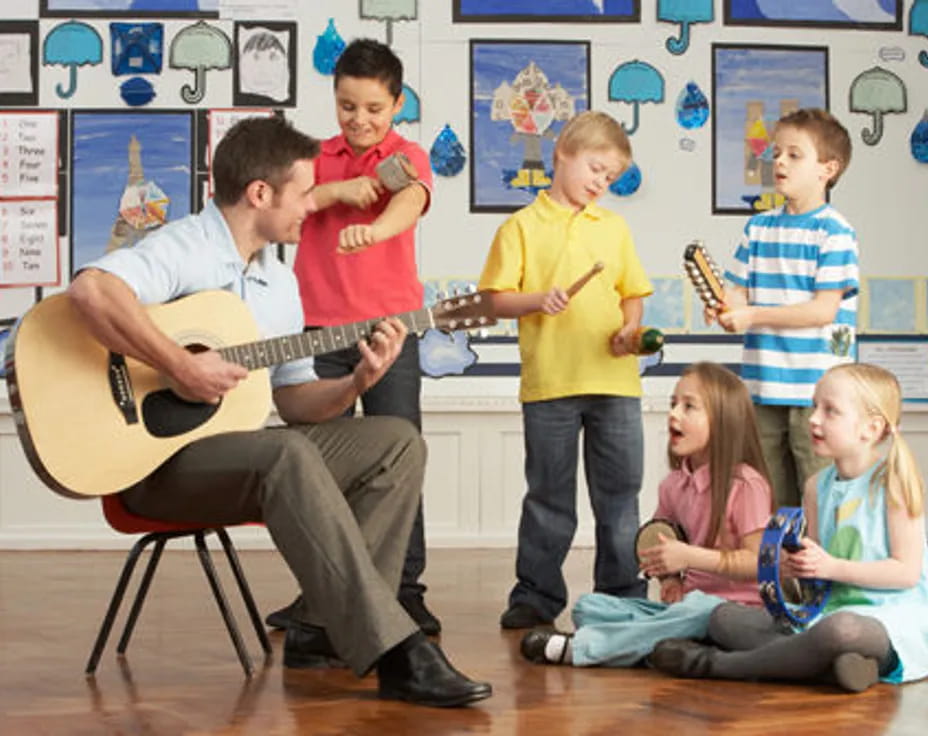 a person playing guitar in front of a group of children