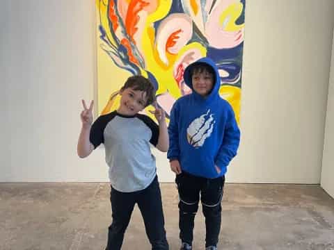 a couple of kids posing for the camera in front of a painting