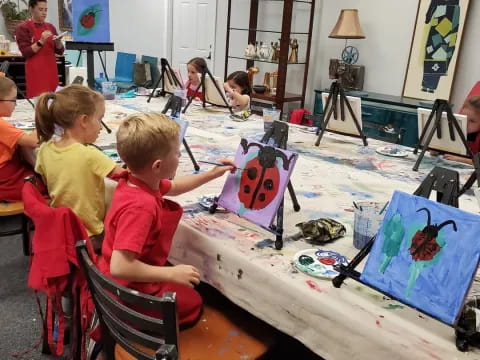 a group of children sitting around a table with art on it