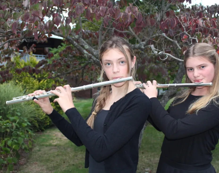 a couple of girls holding bows and arrows in front of a flowering tree