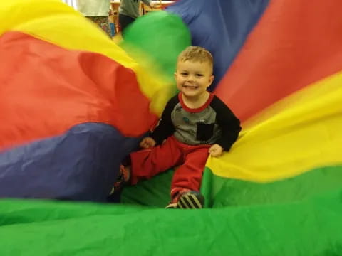 a boy sitting on a colorful slide