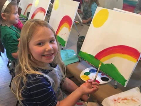 a girl painting a rainbow flag