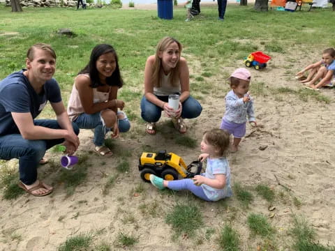 a group of people sitting on the ground with a toy car