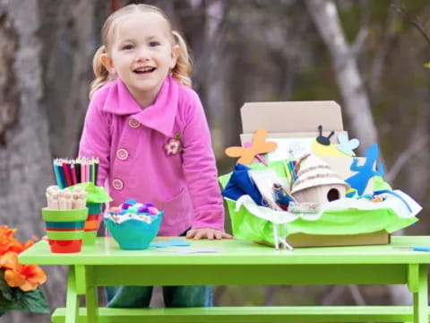 a girl standing next to a table with food and drinks on it