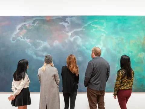 a group of people looking at a large piece of art