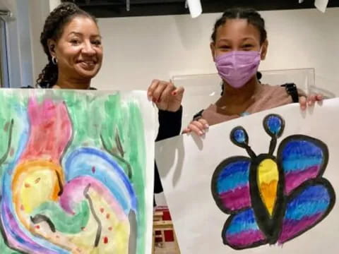 a couple of girls holding up artwork