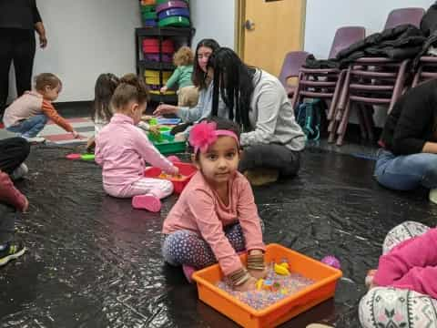 a group of children playing in a room with a person and a child