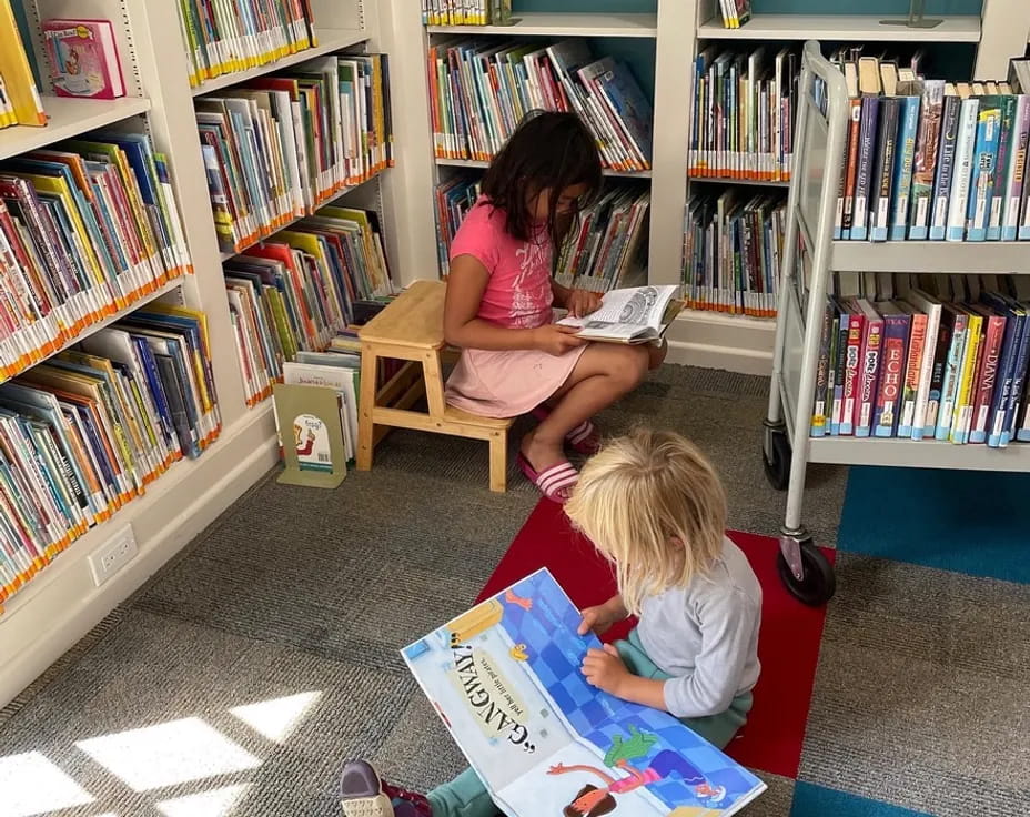 a person reading a book to a young girl in a library
