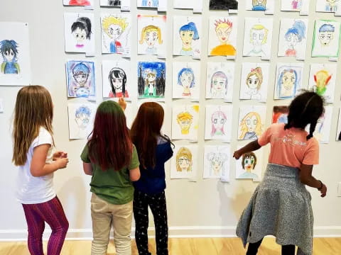 a group of girls looking at a wall of pictures