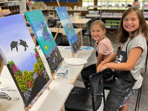 a couple of girls sitting at a table with a surfboard