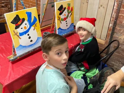 a couple of boys sitting at a table with a christmas tree and a red table with a red