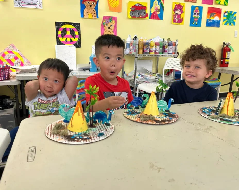 a group of kids sitting at a table with a birthday cake