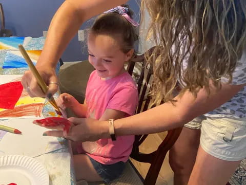 a person helping a child cut a cake