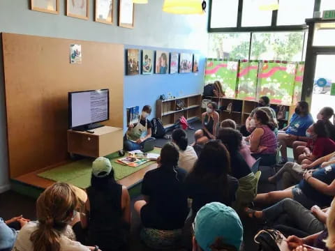 a group of people sitting in a room looking at a screen