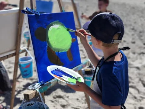 a boy painting on a beach