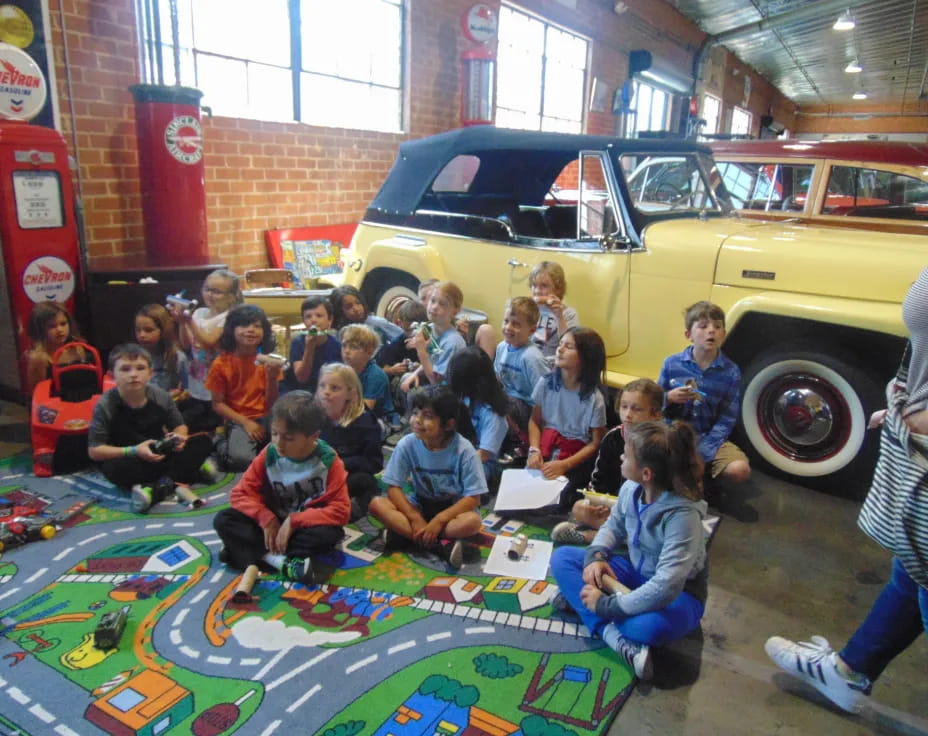 a group of children posing for a photo in front of a yellow truck