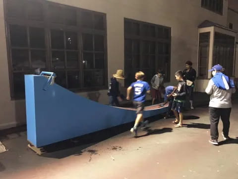 a group of people standing around a blue object outside a building