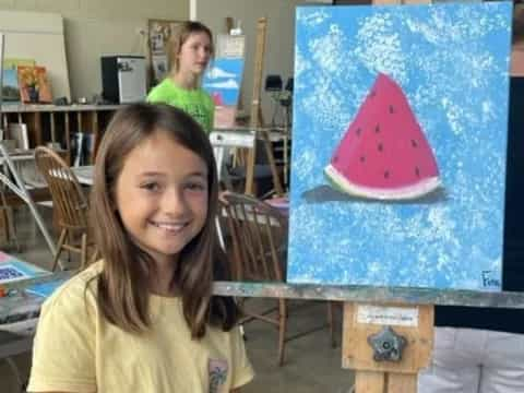 a girl smiling next to a painting