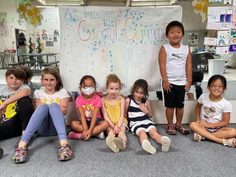 a group of children sitting on the floor in front of a wall