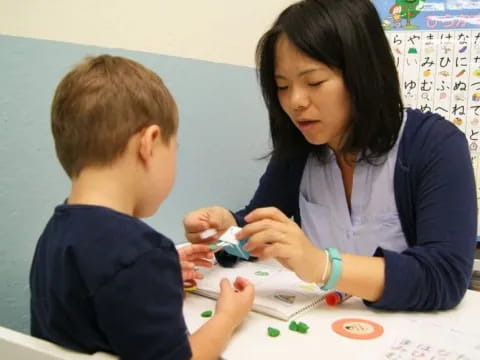 a person and a boy sitting at a table looking at a paper