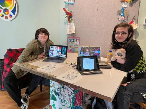 a couple of women sitting at a table with laptops