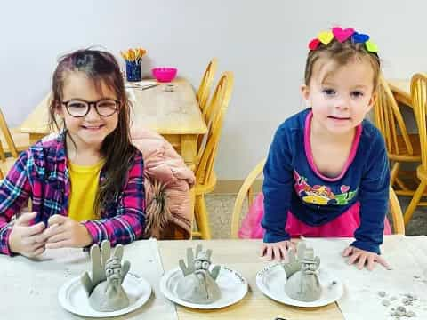 a couple of young girls sitting at a table with food