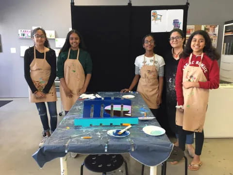 a group of women standing next to a table with plates on it