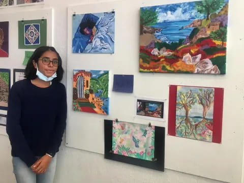 a person standing next to a wall of paintings