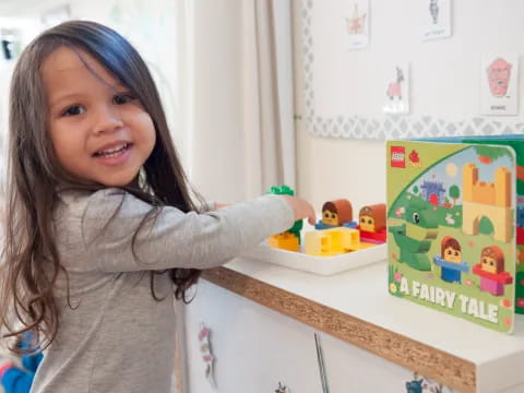 a girl smiling and pointing at a toy