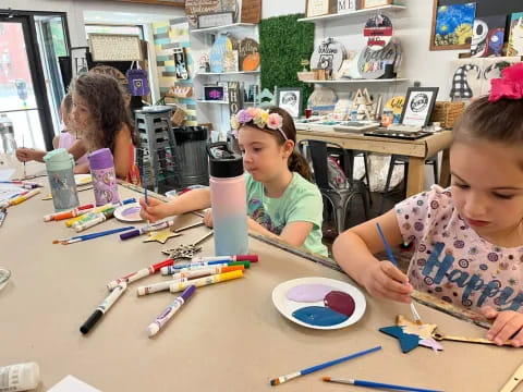 a group of children sitting at a table with colored pencils