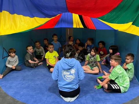 a group of children sitting on the floor in front of a tent