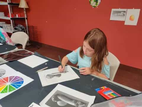 a girl sitting at a table writing on paper