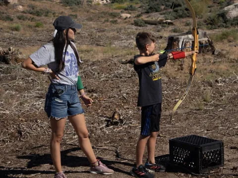 a person and a boy shooting a bow and arrow