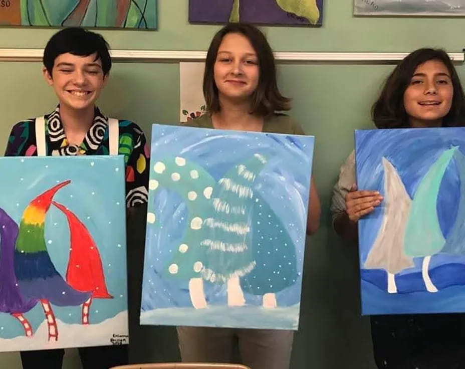 a group of women holding up paintings