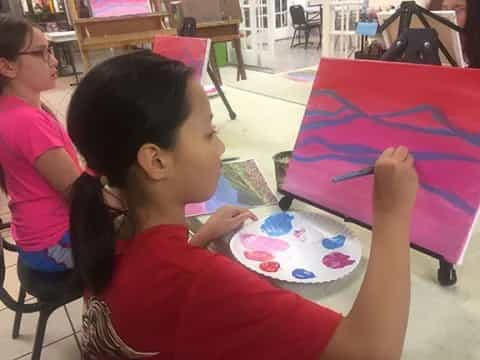 a young girl painting on a table