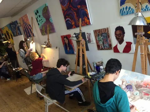 a group of people sitting in a room with art on the wall