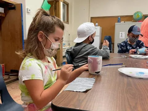 a group of children sitting at a table with a mask on