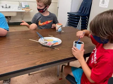 a group of kids sitting at a table with food and drinks