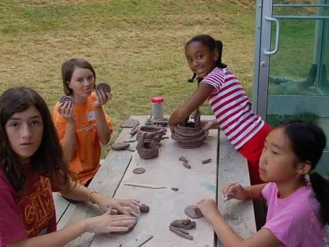 a group of girls sitting around a table with sand on it