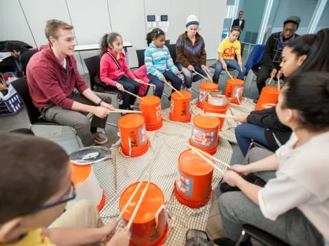 a group of people sitting around a table with orange cups