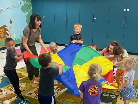a group of children playing on a colorful mat in a classroom