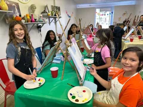 a group of children sitting at a table with plates and cups