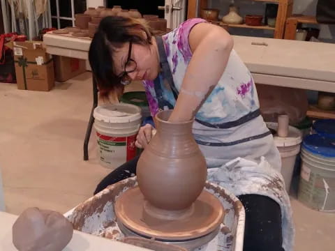 a woman making a clay pot