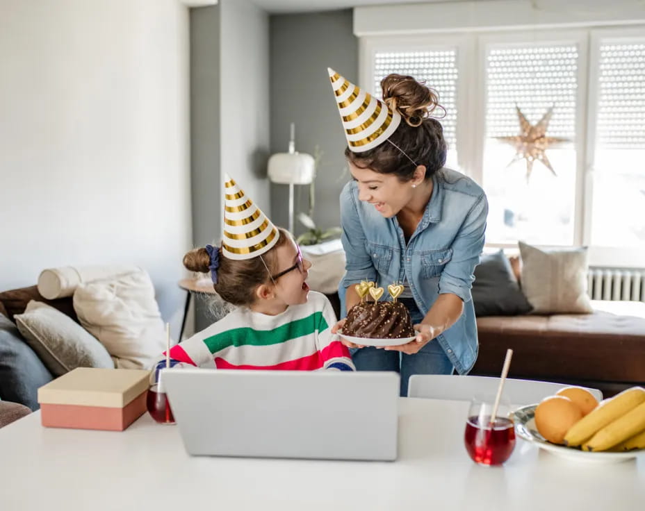 a woman and a child wearing party hats and looking at a laptop