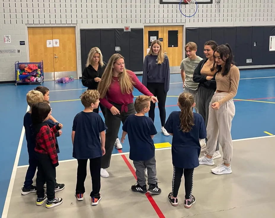 a group of people standing in a room with a person and a group of children