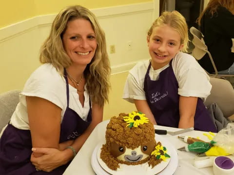 a woman and a girl smiling at a cake
