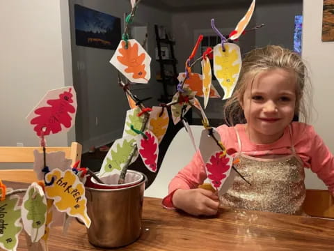 a girl sitting at a table with a vase of flowers